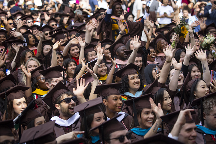 Master's students cheering at a commencement ceremony outside