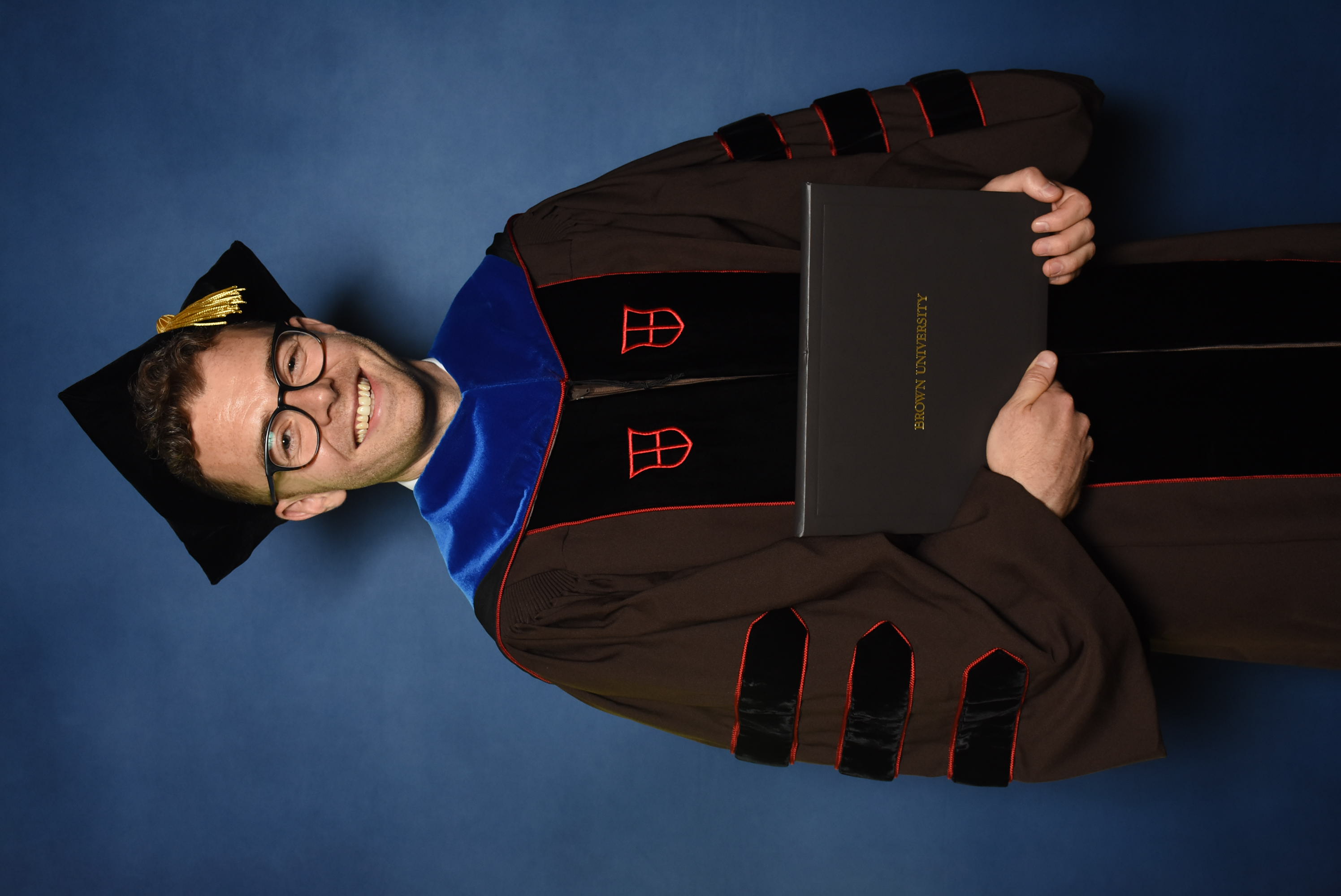 A doctoral student poses for their official graduate photo.